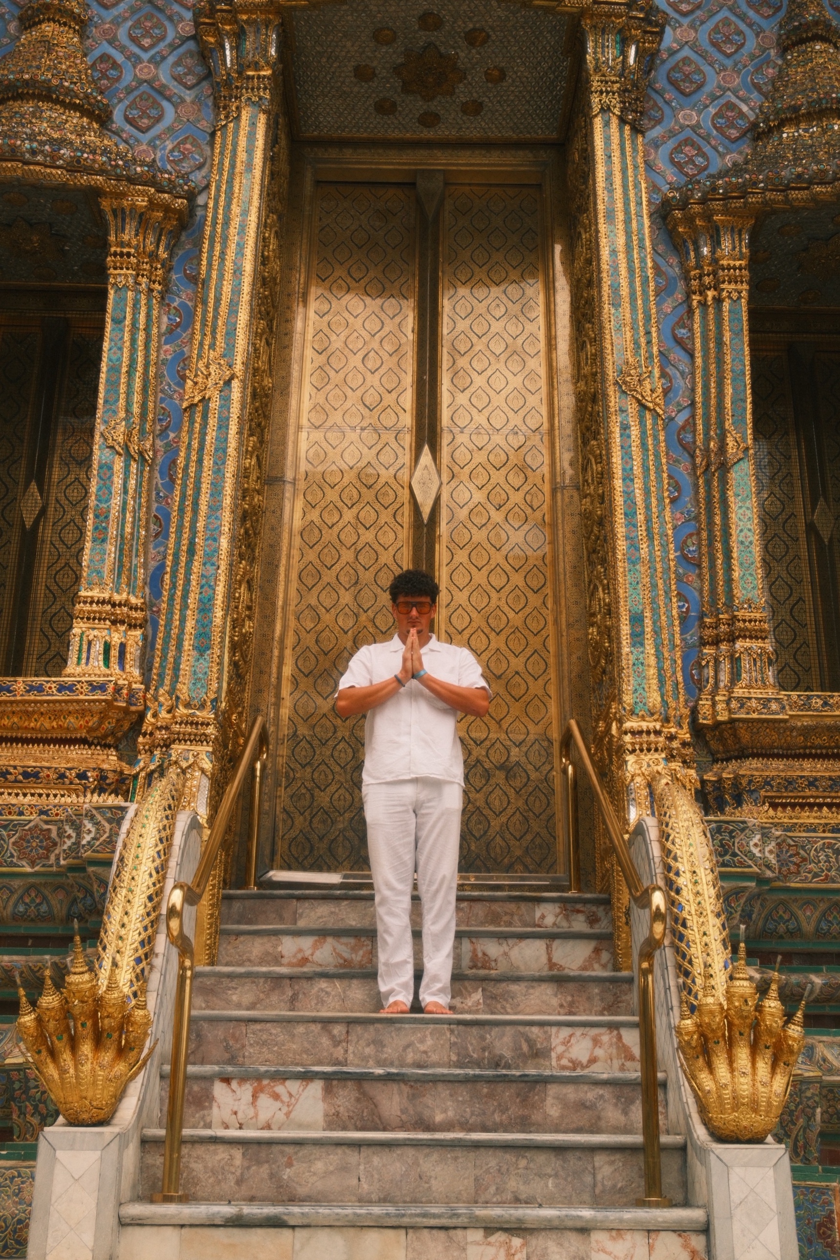 Benjamin en blanc, mains jointes, devant un temple doré